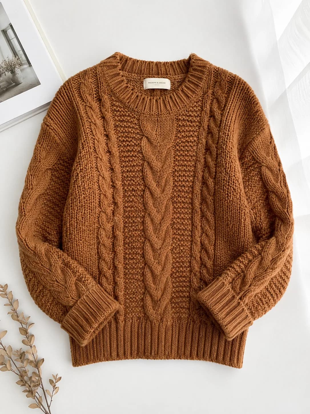 Caramel cable-knit sweater shown as a flat-lay product photo