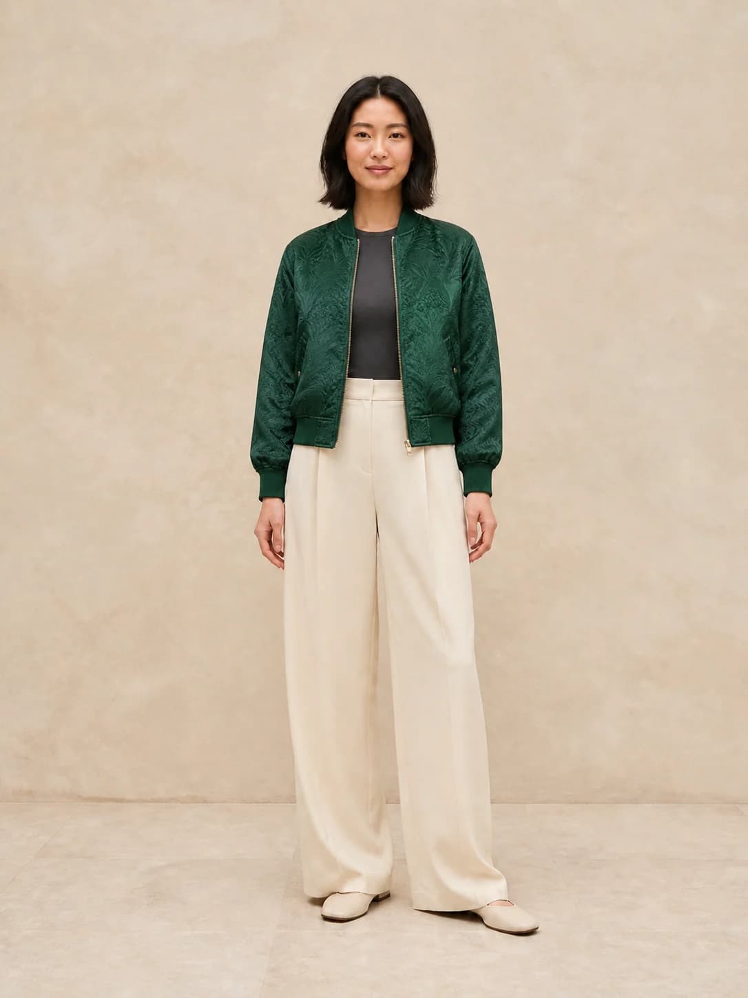 AI virtual try-on result showing the East Asian woman wearing the emerald jacquard bomber jacket